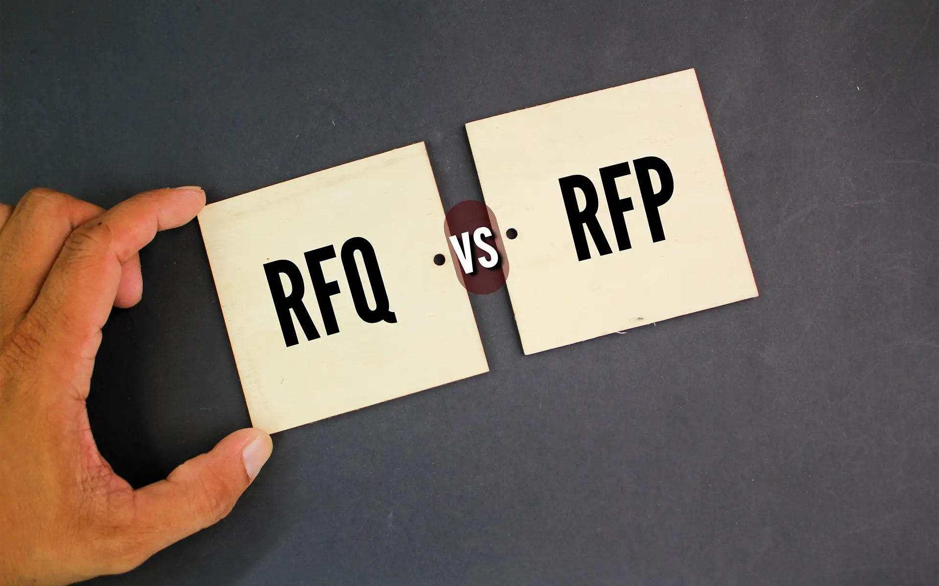 a hand positioning two sticky notes side-by-side with letters rfq vs rfp on a gray background