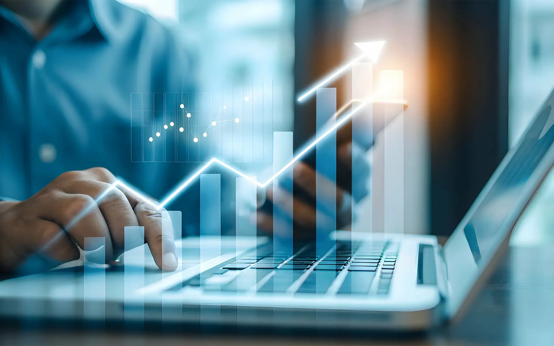 Businessman implementing sales automation tool on laptop with rising revenue graph floating above the keyboard to indicate growth